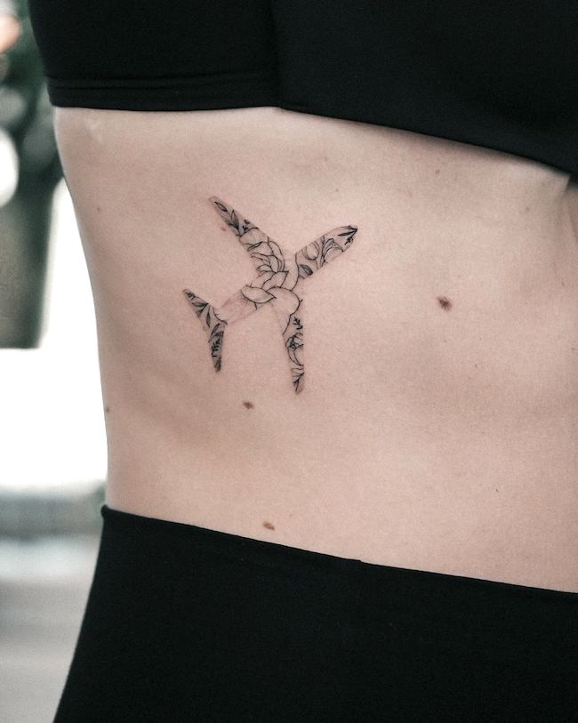 Tatuaggio aereo con motivo floreale sulla cassa toracica di @bunami.ink