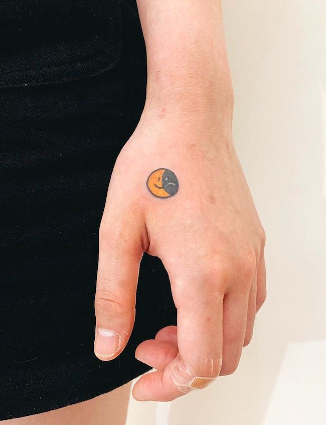 Piccolo tatuaggio con faccia felice e faccia triste di @angustattoo
