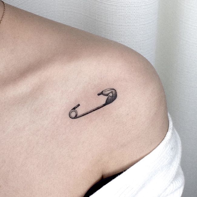 Tatuaggio con spilla di sicurezza sulla spalla da @gyu_tattoo- piccoli tatuaggi significativi