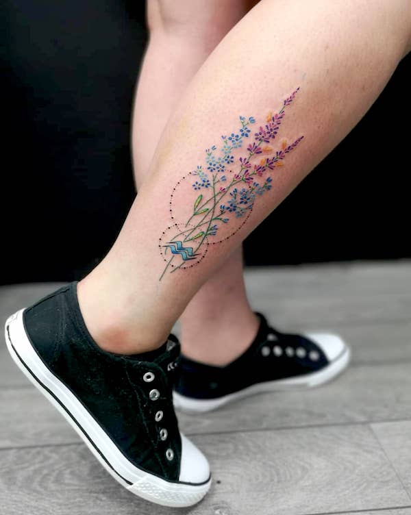 Tatuaggio floreale sul polpaccio con glifo dell'Acquario di @totemastattoo