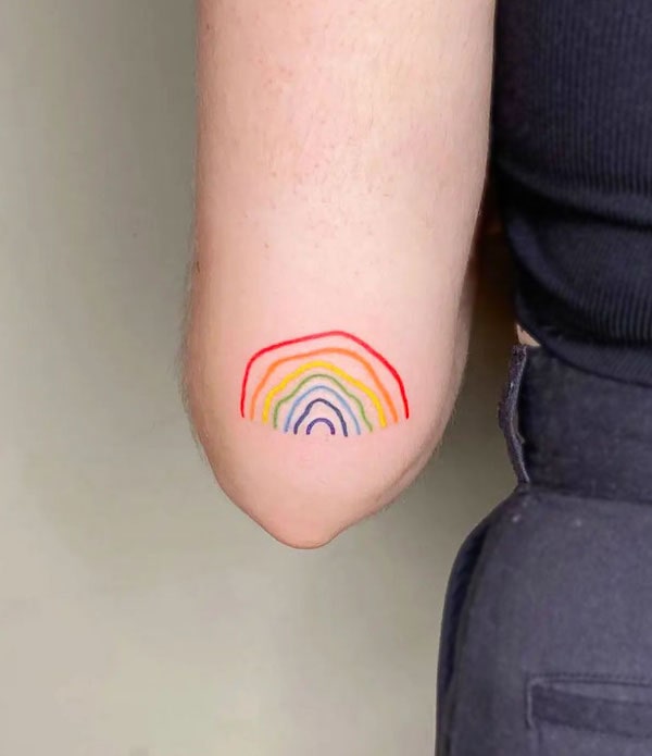 Tatuaggio arcobaleno disegnato a mano sul gomito da @purensonmez.ink